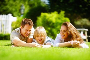 Family laying in green grass on a sunny day laughing